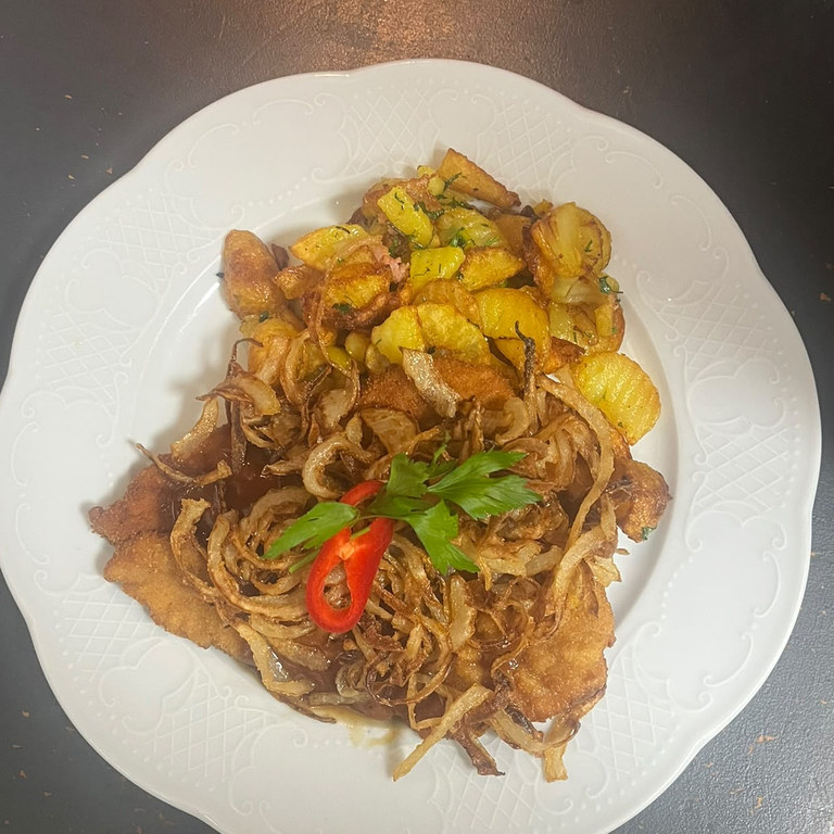 Paniertes Schnitzel mit gerösteten Zwiebeln und Bratkartoffeln