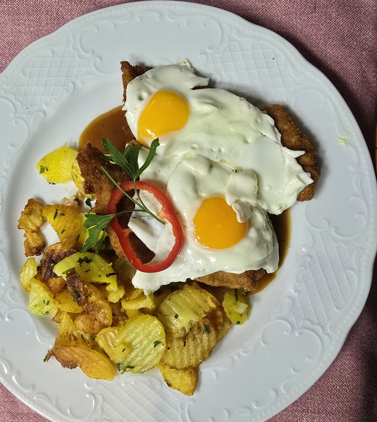 Schnitzel mit zwei Spiegeleiern, Remoulade und Bratkartoffeln